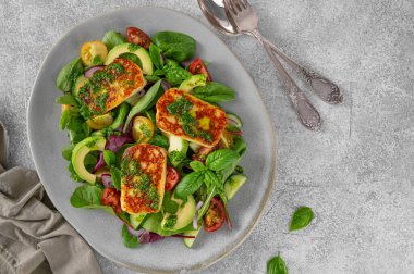 Izgara halloumi peynirli salata, domates, avokado, salatalık ve çimento kaplı pesto sosu. Sağlıklı yiyecekler. Üst görünüm