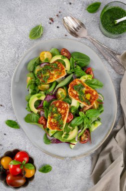 Izgara halloumi peynirli salata, domates, avokado, salatalık ve çimento kaplı pesto sosu. Sağlıklı yiyecekler. Üst görünüm