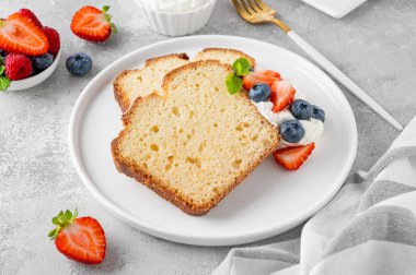 Lezzetli vanilyalı kek, taze böğürtlenler ve gri beton arka planda çırpılmış kremayla servis ediliyor. Seçici odak, boşluğu kopyala