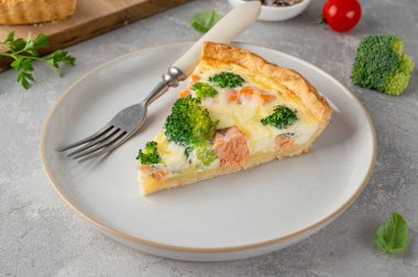 Gri bir arka planda somon, brokoli, peynir ve kremayla ev yapımı tart ya da kiş. Sağlıklı yiyecekler. Seçici odak