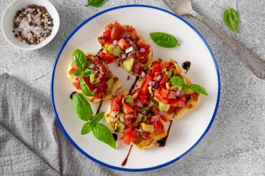 Izgara halloumi peyniri, domates, avokado, soğan ve balzamik soslu beton bir arka planda.