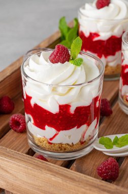 Krem şantili ahududu tatlısı, böğürtlen sosu, kurabiye kırıntıları ve tahta tepside bir bardakta nane yaprağı. Yaz diyeti tatlısı