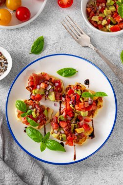 Izgara halloumi peyniri, domates, avokado, soğan ve balzamik soslu beton bir arka planda.