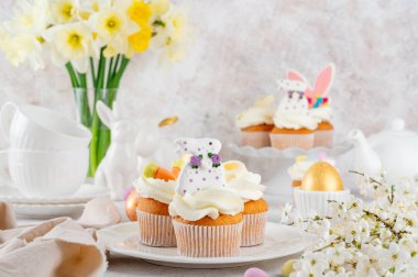 Paskalya çörekleri krema, şeker tavşancıkları, çikolata yumurtaları, jöleli havuçlarla süslenir. Paskalya yemeği kompozisyonu. Boşluğu kopyala