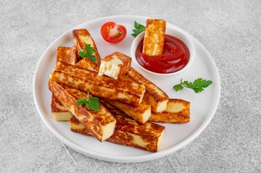 Beton zeminde beyaz bir tabakta domates soslu kızarmış halloumi peyniri.