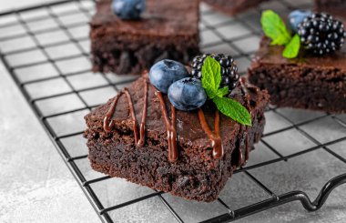 Çikolatalı kek kareleri, çikolata jöleli ve gri beton arka plandaki fırın rafında taze meyveler. Tatlı nefis.