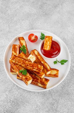 Beton zeminde beyaz bir tabakta domates soslu kızarmış halloumi peyniri.