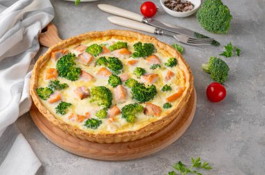 Gri bir arka planda somon, brokoli, peynir ve kremayla ev yapımı tart ya da kiş. Sağlıklı yiyecekler. Seçici odak
