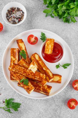 Beton zeminde beyaz bir tabakta domates soslu kızarmış halloumi peyniri.