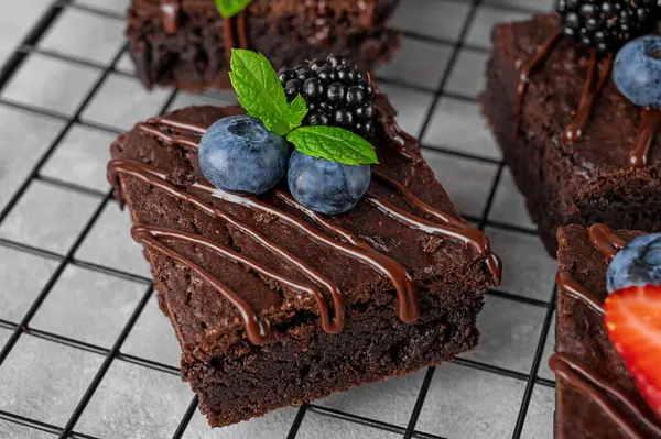Çikolatalı kek kareleri, çikolata jöleli ve gri beton arka plandaki fırın rafında taze meyveler. Tatlı nefis.