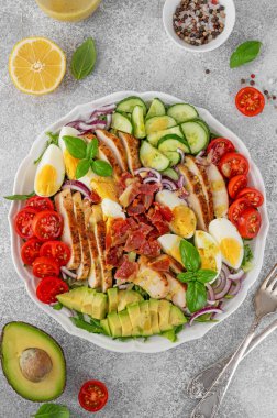 Kızarmış tavuk göğsü, doğranmış avokado, domates, pastırma, salatalık, haşlanmış yumurta ve yeşil yapraklı sağlıklı Cobb salatası. Üst görünüm