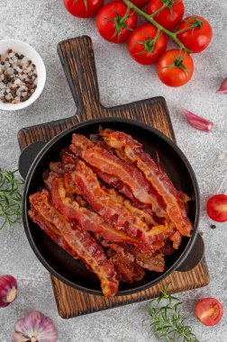 Kahvaltıda domuz pastırması, domatesli, sarımsaklı, biberiyeli ve çimento kaplı dökme demir bir tavada. Üst görünüm