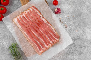 Tahta bir tahtada kahvaltı için çiğ pastırma dilimleri, domates, sarımsak, biberiye ve çimento kaplı baharatlar. Üst görünüm, alanı kopyala