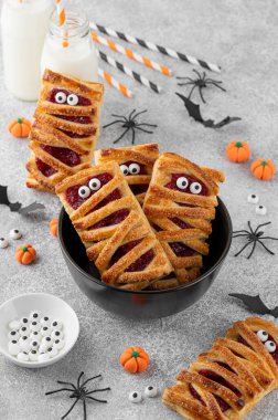 Cadılar Bayramı mumyaları kiraz dolgulu pastalar ve gri beton arka planda şeker gözler. Komik yemek fikri. Tatil tatlısı. Üst görünüm