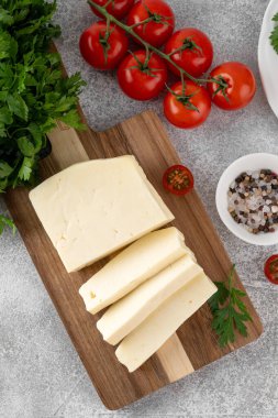 Ahşap bir tahtanın üzerinde beyaz peynir halloumi ve çimento kaplı otlar ve domatesler. Üst görünüm