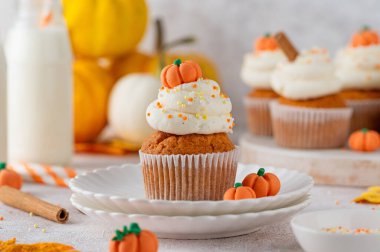 Balkabağı aromalı kekler tereyağlı krema, şeker parçacıkları ve üstünde küçük tatlı balkabakları. Şükran Günü ya da Cadılar Bayramı