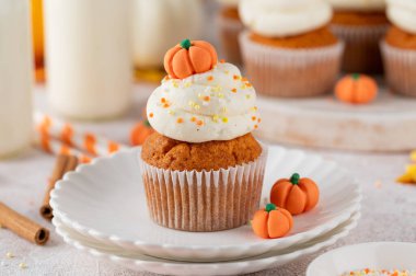 Balkabağı aromalı kekler tereyağlı krema, şeker parçacıkları ve üstünde küçük tatlı balkabakları. Şükran Günü ya da Cadılar Bayramı