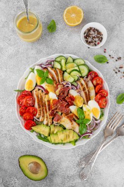 Kızarmış tavuk göğsü, doğranmış avokado, domates, pastırma, salatalık, haşlanmış yumurta ve yeşil yapraklı sağlıklı Cobb salatası. Üst görünüm