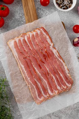 Tahta bir tahtada kahvaltı için çiğ pastırma dilimleri, domates, sarımsak, biberiye ve çimento kaplı baharatlar. Üst görünüm, alanı kopyala