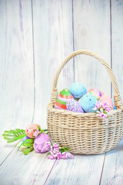 Easter, wicker basket with Easter eggs on a light wooden background. High quality photo