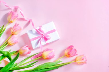 spring card, tulips and gift with pink ribbon on pink background, womens day, mothers day. High quality photo