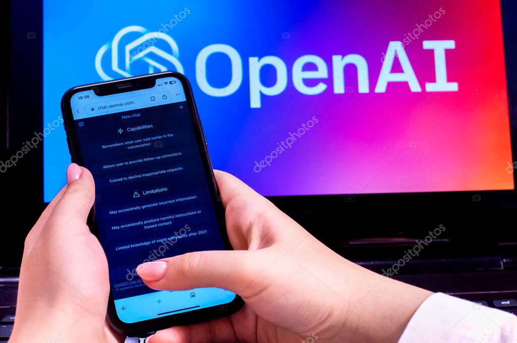 OpenAI logo on laptop monitor and phone in hand using GPT chat. High quality photo