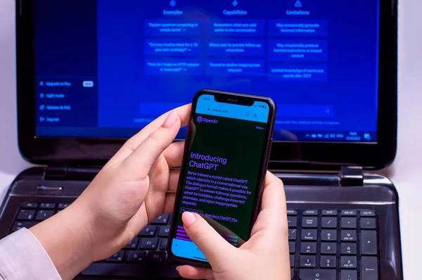 Bilgisayarlı bir kızın arka planında açık sohbet GPT 'si olan bir telefon var. Yapay zeka. Ukrayna - 12 Mart 2023 Yüksek kaliteli fotoğraf