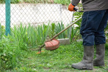 Adam çim biçme makinesiyle çim biçiyor, evin yakınındaki bahçede çalışıyor. Yüksek kalite fotoğraf