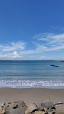 Sabit Tutunaklı: Uzak Tekneli Huzurlu Sahil ve Açık Mavi Gök Sahili ve küçük dalgalı kayalıklar