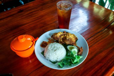 Kızarmış ördek, pilav, sebze, baharatlı Sambal ve tatlı buzlu çay.