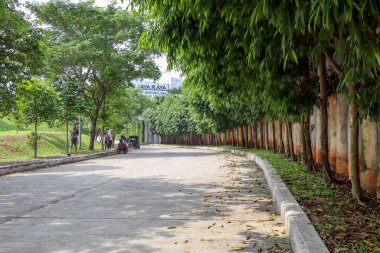 Tangerang Selatan, Endonezya - 2 Haziran 2024: Beton Yol Ağaçlarla çevrili PB Jaya Raya badminton spor arenası, Bintaro, Tangerang Selatan, Endonezya