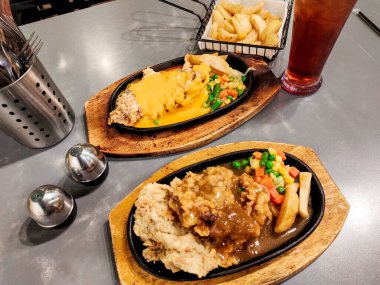 Bir çift çıtır biftek, un kaplı biftek, sebze, barbekü sosu, peynir sosu, yanında da patates kızartması.