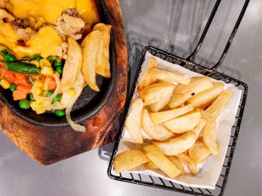 Bir çift çıtır biftek, un kaplı biftek, sebze, barbekü sosu, peynir sosu, yanında da patates kızartması.