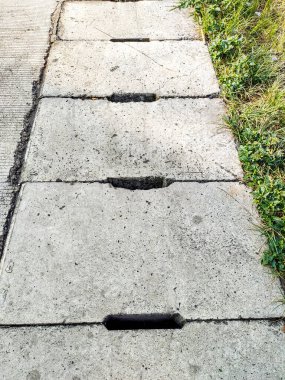 Bandung City, Endonezya 'da bir yaya yolunun ve çimenli bir alanın yanında bulunan beton drenaj kapağı