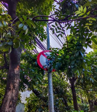 Bandung, Endonezya - 19 Mayıs 2024: Hiçbir trafik işareti ağaç yaprakları tarafından neredeyse tamamen gizlenmiş değil, bu da açıkça görülmesini zorlaştırıyor