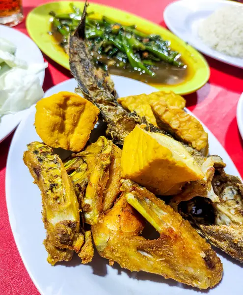 stock image Pecel lele, fried chicken, tofu, tempeh, sambal pecel, fresh vegetables, and stir-fried water spinach, a traditional Indonesian street food menu