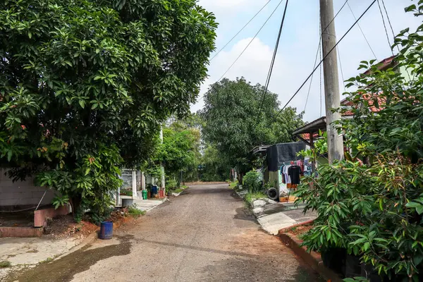 stock image Cikarang, Indonesia - July 2nd 2024 : A serene street view within a Residential Real Estate Complex with Single-Story Homes and Lush, Shady Trees