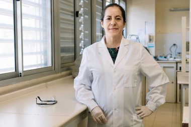 Laboratuvarda çalışan bir kadın kameraya bakıp gülümsüyor. Olumlu düşünüyorum..