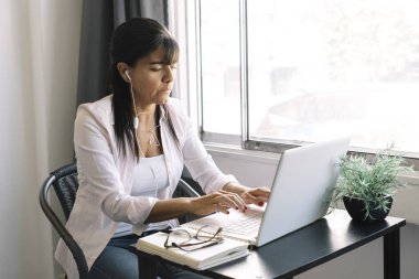 İş kadını dizüstü bilgisayarda çalışıyor evde oturuyor ve Coronavirus veya Covid-19 karantinası sırasında ev işleri ile uğraşıyor..