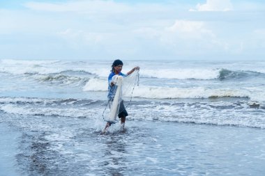 Central American fisherman preparing net on tropical beach.