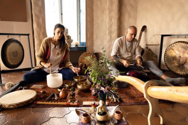 Kadın müzik kasesi çalıyor, erkek de melodik davul çalıyor, titreşim aletleri. Ses terapisi, alternatif tıp. Boşluğun negatif enerjiden temizlenmesi.