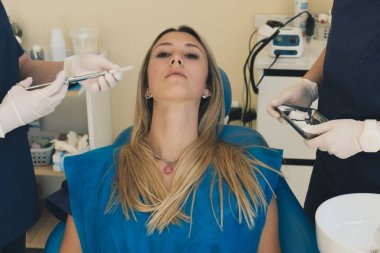 Diş muayenehanesinde diş muayenesi yapan güzel genç bir kadın. Diş hekimliği kürsüsünde ciddi bir kızın portresi..