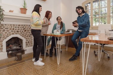 Dört meslektaştan oluşan bir grup, rahat bir toplantının, fikirlerin paylaşılmasının ve şömineyle rahat bir ofis ortamında çalışmanın keyfini çıkarıyor..