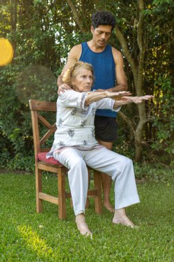 Üst düzey kadın, rahat bir ortamda fizyoterapistin yardımıyla esneme hareketleri ve refahı destekliyor.