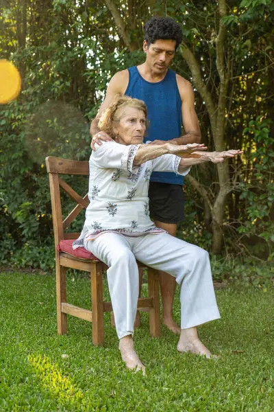 Üst düzey kadın, rahat bir ortamda fizyoterapistin yardımıyla esneme hareketleri ve refahı destekliyor.