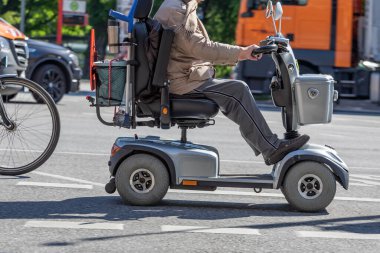 Elektrikli sandalyedeki yaşlı adam sokaklarda geziyor.