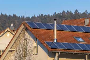 Çatıda güneş panelleri ve paslanmaz çelik bacası olan ayrı bir ev.