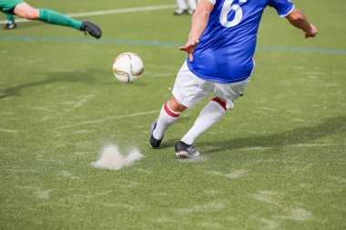 Yapay çimenlikteki amatör futbolcu topu atıyor.