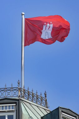 Yeşil bakır çatılı bir binada hamburg bayrağı dalgalanıyor.