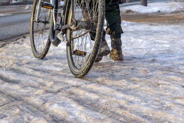 Woman pushes her bike along a dangerously icy bike path clipart